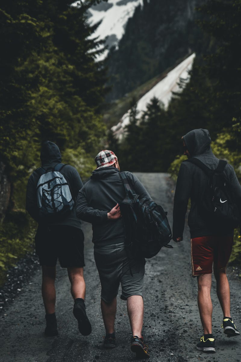 Three friends walking on a mountain trail in Kitzbühel, Tirol, Austria, amidst lush greenery.
